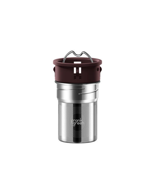 A stainless steel travel tumbler with a dark brown silicone lid and a metal carrying loop, featuring the 'frank grill' logo on the front, set against a plain white background.
